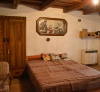 Hálószoba egy családi házban fa szekrénnyel, ággyal és képpel a falon.