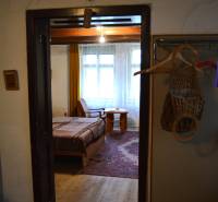 Családi ház belső tere ággyal és fa padlóval, az ajtón keresztül látható egy szoba.