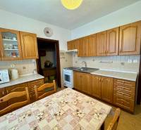 Konyha fa szekrényekkel és étkezőasztallal, amely alkalmas egy háromszobás lakáshoz.