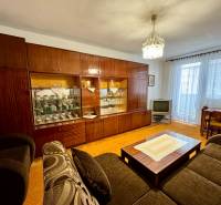 Nappali rusztikus nappali falakkal és TV-vel egy háromszobás lakásban.