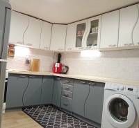 Konyha családi házban fehér és szürke szekrényekkel, fa hatású padlóval.