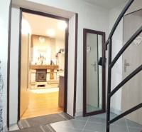 Családi ház belső tere lépcsőházzal, fa dekorációjú padlóval és kandallóval.