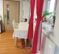 Ebédlő egy családi házban piros függönnyel, asztallal és fa dekorációjú padlóval.