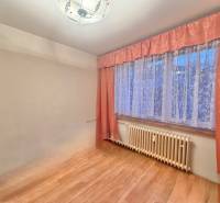 Szoba egy háromszobás lakásban fa dekor padlóval és függönyökkel.