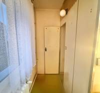 Keskeny folyosó egy háromszobás lakásban, padlóval és fehér ajtókkal.