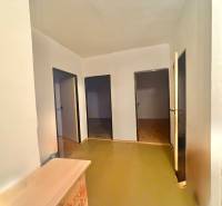 Folyosó egy 3 szobás lakásban világos falakkal és három ajtóval, fa dekorációjú padlóval.