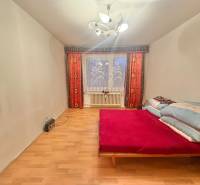 Hálószoba egy háromszobás lakásban ággyal, fa dekorációjú padlóval és világítással.