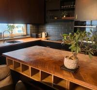 Konyha egy kétszobás lakásban fa dekorációjú padlóval és fekete konyhabútorral.