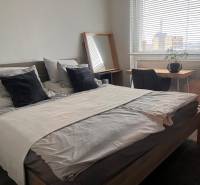 Hálószoba egy kétszobás lakásban ággyal, íróasztallal és fa mintázatú padlóval.