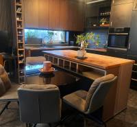 Konyha egy kétszobás lakásban fekete szekrényekkel és fa dekorációjú padlóval.