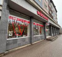 Kereskedelmi helyiségek Poprádon, feltűnő piros logóval az épületen.