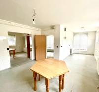 Tágas szoba faasztalokkal és radiátorokkal egy családi házban.