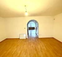 Szoba boltíves átjáróval és fa dekorációjú padlóval egy családi házban.