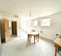 Családi ház belső tere üres szobával, asztalokkal és fehér falakkal.