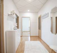 Négyszobás lakás folyosója fa dekoros padlóval, egyszerűen berendezve.