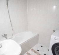 Fürdőszoba zuhanyzó káddal, mosdóval és mosógéppel egy 4 szobás lakásban.