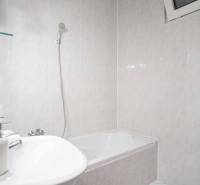 Fürdőszoba káddal és mosógéppel egy 4 szobás lakásban. A falakat világos csempék borítják.