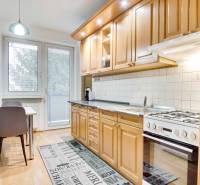 Konyha egy 4 szobás lakásban fa mintázatú padlóval és étkezőasztallal.