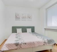 Hálószoba világos ággyal, fa dekoros padlóval és díszes képekkel a 4 szobás lakásban.