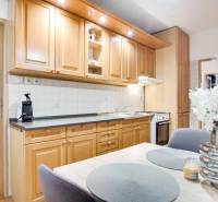 Konyha egy 4 szobás lakásban fa szekrényekkel, virágokkal és étkezőasztallal.