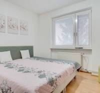 Hálószoba egy 4 szobás lakásban virágos dekorációkkal és falra szerelt televízióval.