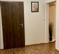 Előszoba egy háromszobás lakásban, mintás padlóval, fa dekorral és egyszerű díszítéssel.