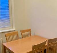 Étkezőasztal négy székkel egy háromszobás lakásban, fa dekorációjú padlóval.