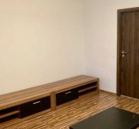 Nappali szoba fa mintás padlóval egy háromszobás lakásban, világos falak, fa bútorok.