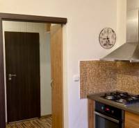 Konyha egy háromszobás lakásban gáz tűzhellyel, mozaik csempével és fa dekor padlóval.