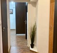 Előszoba egy háromszobás lakásban, fa dekoros padlóval és beépített szekrényekkel.