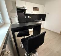 Konyha ülőhellyel és fa dekoros padlóval egy egyszobás lakásban.