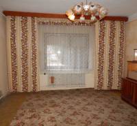 Szoba családi házban virágmintás tapétával és központi csillárral.