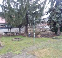 Családi ház kertje Dunamocs községben, filagóriával és tűlevelű fákkal.