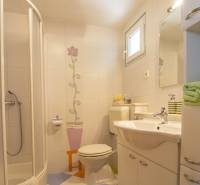 Fürdőszoba a Nyaraló Apartmanban virágmintás csempékkel és fehér mosdókagylóval.