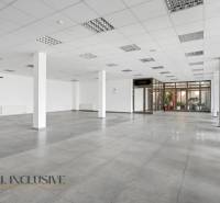 Tágas üzlethelyiségek csempével, nagy ablakokkal és fehér falakkal.