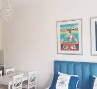 Egy szobás lakás belső tere konyhával, csillárral és képekkel a kék ágy felett.