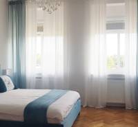 Hálószoba franciaággyal, képekkel és fa dekorációjú padlóval egy egyszobás lakásban.