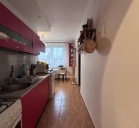 Konyha egy kétszobás lakásban, fa dekoros padlóval, háttérben étkező sarokkal.