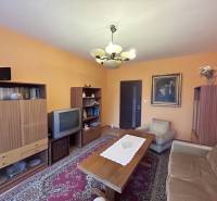 Nappali retro bútorokkal egy kétszobás lakásban, fa dekorációjú padlóval, szőnyegekkel.