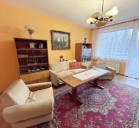 Nappali egy kétszobás lakásban, fa mintázatú padlóval és szőnyeggel.