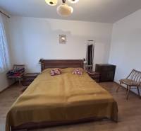 Hálószoba egy kétszobás lakásban ággyal, székekkel és fa dekorációjú padlóval.