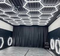 Sötét dekorral rendelkező üzlethelyiség hatszögletű LED világítással a mennyezeten és a falakon.