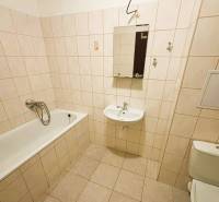 A kétszobás lakás fürdőszobája klasszikus káddal és semleges tónusú csempével.