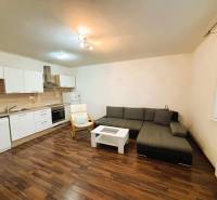 Nappali egy kétszobás lakásban sarokkanapéval és konyhabútorral.