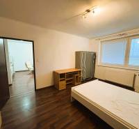 Hálószoba egy kétszobás lakásban fa dekorációjú padlóval és egyszerű bútorokkal.