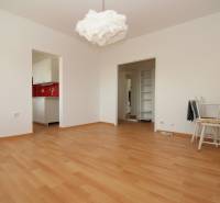 Szoba fa mintázatú padlóval, fehér bútorokkal és piros konyhai fallal.