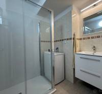 Fürdőszoba egy kétszobás lakásban mosdóval, zuhanyzóval és mosógéppel.