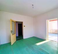 Családi ház belső tere nyitott ajtókkal, fehér falakkal és zöld padlóval.