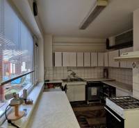 Konyha családi házban háztartási gépekkel, csempékkel és teraszra néző ablakkal.