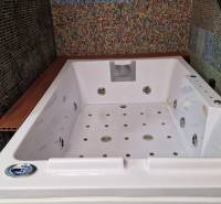 A családi ház fürdőszobájában egy nagy hidromasszázs kád található, színes mozaik csempével díszítve.